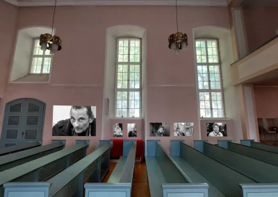 Auf dem Foto ist zu sehen, wie die schwarz-weiß Portraits unterschiedlicher Menschen an der rechten Wand in der Stadtkirche Offenbach gezeigt werden.